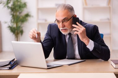 Eski erkek işveren ofiste oturuyor.