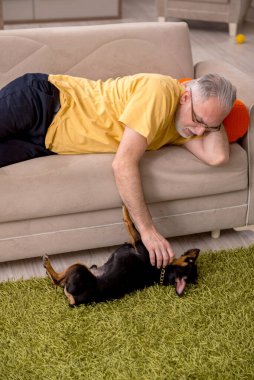 Evde köpeği olan yaşlı bir adam.