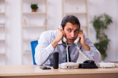 Masasında çalışan genç bir erkek çağrı merkezi operatörü.