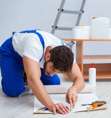 Tamirci, duvar kağıdıyla evde tadilat yapıyor.