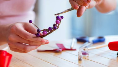 Kadın evde mücevher yapıyor.