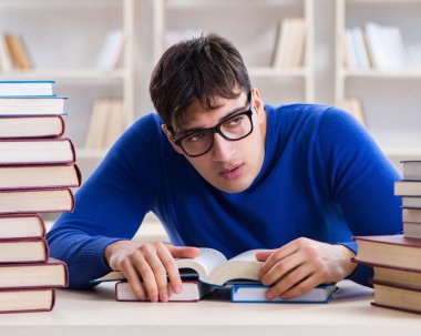 Erkek öğrenci üniversite kütüphanesinde sınava hazırlanıyor.