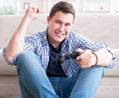 Genç adam evde bilgisayar oyunu oynuyor.