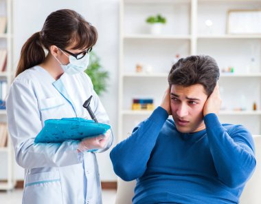 Doktor muayene sırasında hastaların kulaklarını kontrol ediyor.