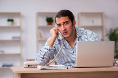 Genç erkek çalışan ofiste oturuyor.