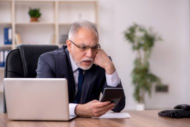 Yaşlı muhasebeci ofiste oturuyor.