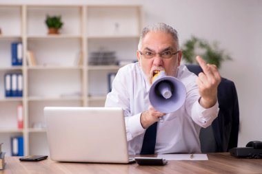 İş yerinde megafon tutan yaşlı bir erkek işçi.