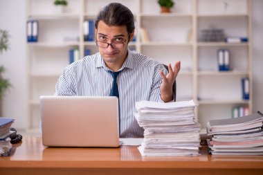 Ofisteki aşırı işten memnun olmayan genç bir erkek işçi.