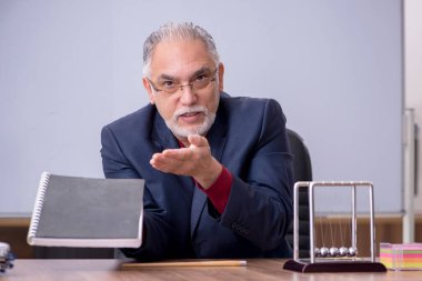 Sınıfta oturan eski bir fizikçi öğretmen.