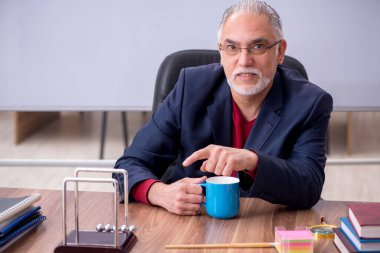 Sınıfta oturan eski bir fizikçi öğretmen.