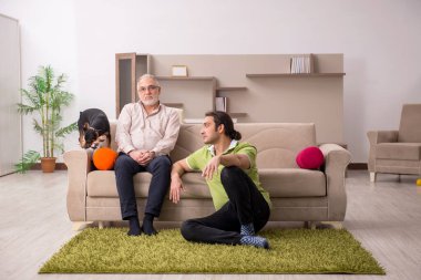 Evde köpekli iki adam.