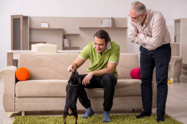 Evde köpekli iki adam.