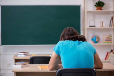 Yeşil panonun önünde genç bir erkek öğrenci.