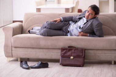 Yorgun genç işadamı işten sonra eve geliyor.