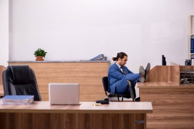 Genç erkek çalışan işyerinde oturuyor.