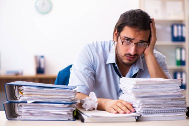 Ofisteki aşırı işten memnun olmayan genç bir erkek işçi.