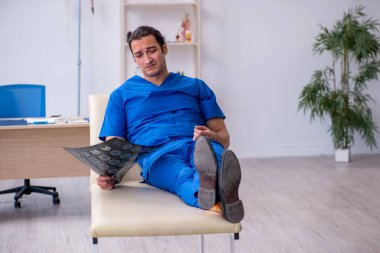 Genç erkek doktor radyoloji uzmanı gece vardiyasından sonra mutsuz oluyor.