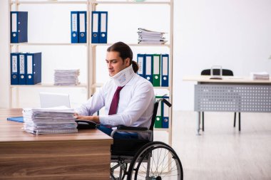 İş yerinde tekerlekli sandalyede oturan boynu yaralı genç bir erkek.