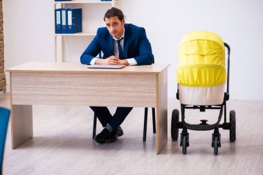 Genç erkek çalışan işyerinde çocuğa bakıyor.