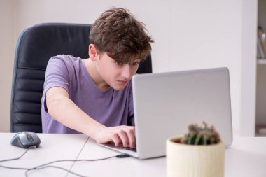 Okullu çocuk evde bilgisayar oyunu oynuyor.