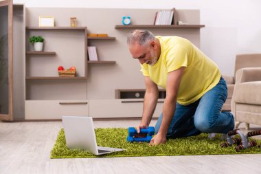 Yaşlı adam evde spor egzersizleri yapıyor.