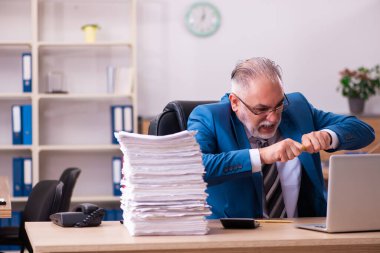 Ofisteki aşırı işten memnun olmayan yaşlı bir erkek işçi.