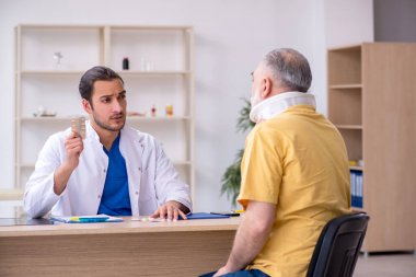 Yaşlı boynu yaralı bir adam genç erkek doktoru ziyaret ediyor.