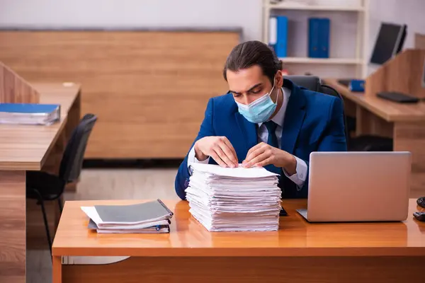 Joven empleado masculino que trabaja en la oficina con máscara — Foto de Stock