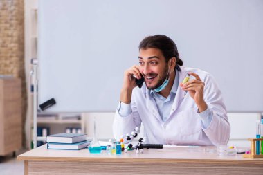 Sınıfta oturan genç erkek kimya öğretmeni.