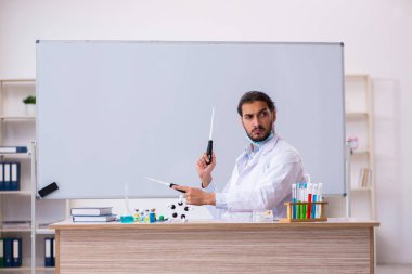 Sınıfta oturan genç erkek kimya öğretmeni.