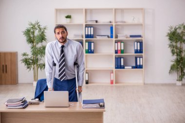 Ofiste çalışan genç bacağı yaralı bir erkek işçi.