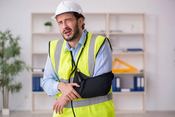 Young arm injured male architect working in the office