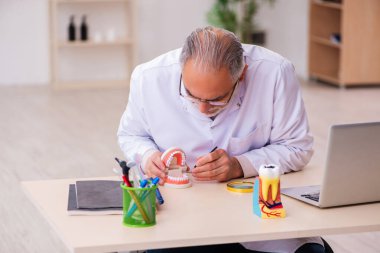Klinikte çalışan yaşlı erkek dişçi.