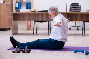 Ofiste spor egzersizleri yapan eski bir işadamı.