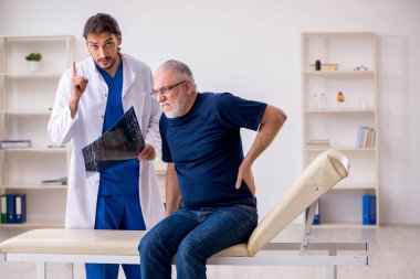 Yaşlı erkek hasta genç erkek doktor radyolojisti ziyaret ediyor.