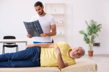 Yaşlı erkek hasta, genç erkek doktor masörünü ziyaret ediyor.