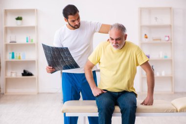 Yaşlı erkek hasta, genç erkek doktor masörünü ziyaret ediyor.