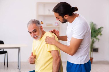 Yaşlı erkek hasta, genç erkek doktor masörünü ziyaret ediyor.