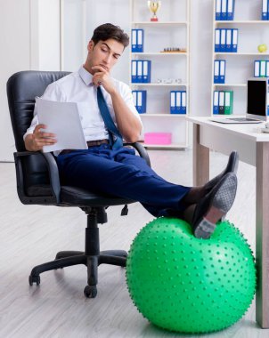 Genç işadamı iş yerinde spor yapıyor.