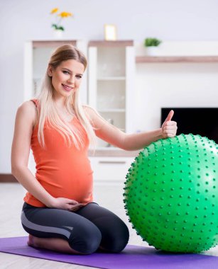 Evde doğum egzersizi yapmaya hazırlanan genç bir kadın.