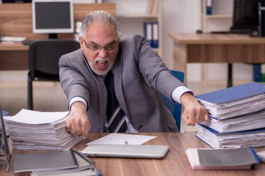 Ofisteki aşırı işten memnun olmayan yaşlı bir erkek işçi.