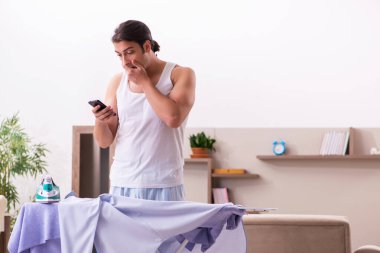 Genç erkek çalışan sabah ütü yapıyor.