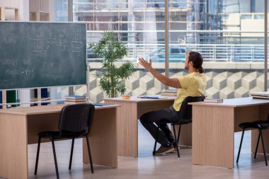 Sınıfta oturan genç erkek öğrenci.