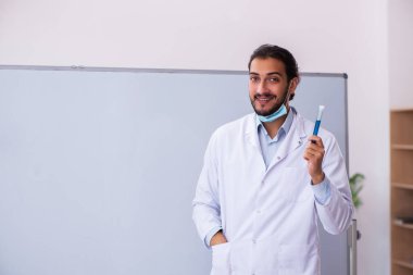 Sınıfta oturan genç erkek kimya öğretmeni.