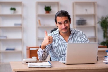 Genç erkek çalışan ofiste oturuyor.