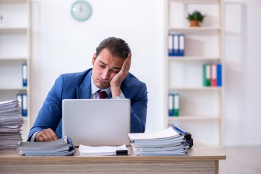 Ofisteki aşırı işten memnun olmayan genç bir erkek işçi.