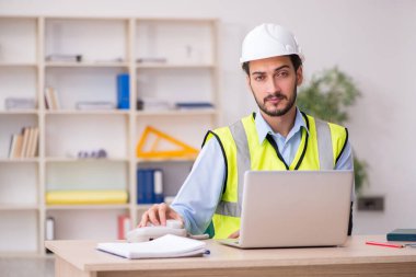 Genç kollu yaralı erkek mimar ofiste çalışıyor.