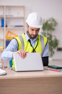 Genç kollu yaralı erkek mimar ofiste çalışıyor.