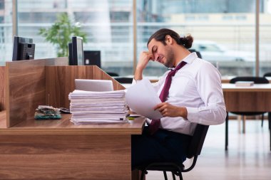 Genç bir erkek işçi ve ofiste çok fazla iş var.