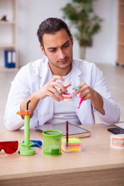 Klinikte çalışan genç erkek dişçi.